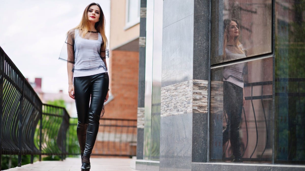 Woman wearing black leather pants styled with ankle boots, showing what shoes to wear with leather pants for a modern street style look.