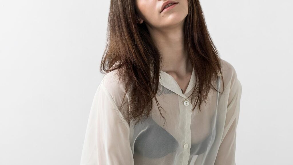 What to Wear Under Sheer White Blouse 1 What to wear under a sheer white blouse – woman wearing a sheer white blouse layered over a neutral bra, showing how to style transparent white blouses.